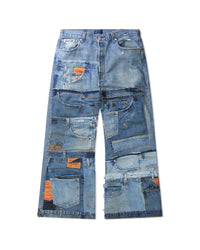 A pair of wide-leg denim jeans made from patchwork-style stitching of multiple blue denim jeans, featuring various pocket details and orange brand patches, laid flat on a white background.